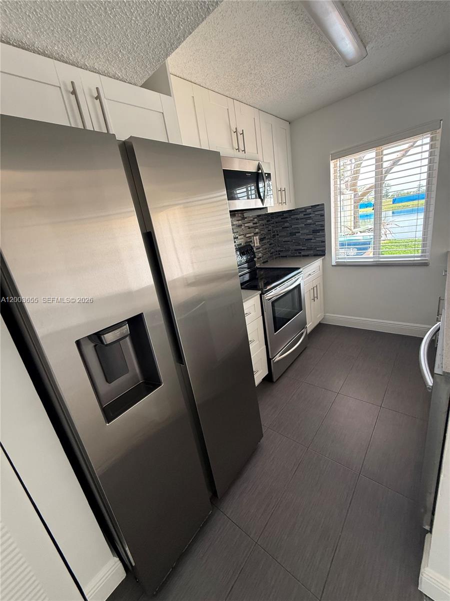 203 Riviera Circle, Unit 203 Weston, FL 33326 - Photo 7 of 30 a kitchen with granite countertop stainless steel appliances a refrigerator a sink a stove a microwave oven and a window