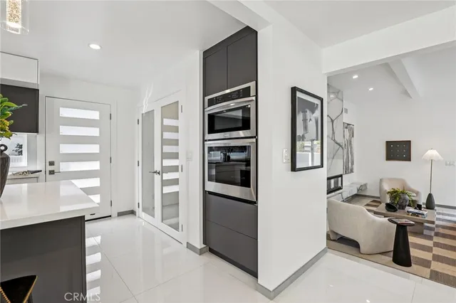 a living room with stainless steel appliances furniture a large window and a kitchen view