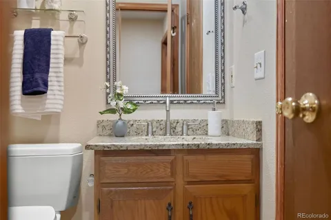 a bathroom with a granite countertop sink a toilet and mirror
