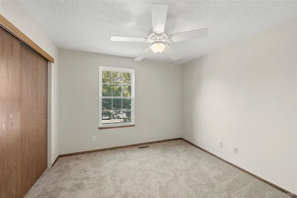 an empty room with windows and fan