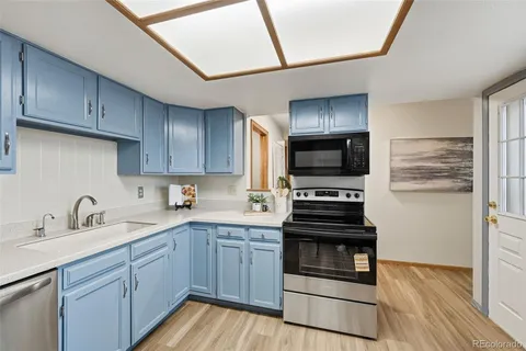 a kitchen with a sink stainless steel appliances and wooden floor