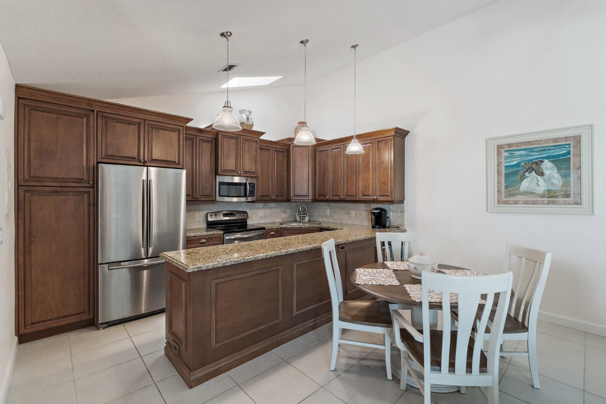 1801 South Us Highway, Unit 8D Jupiter, FL 33477 - Photo 6 of 36 a kitchen with a refrigerator a stove a sink a dining table and chairs