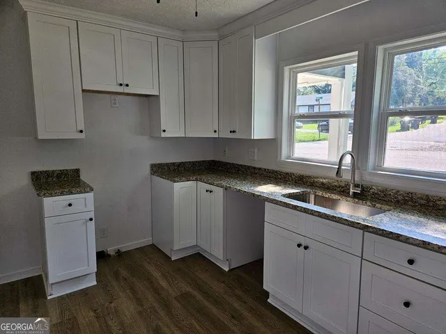 a kitchen with granite countertop white cabinets and sink