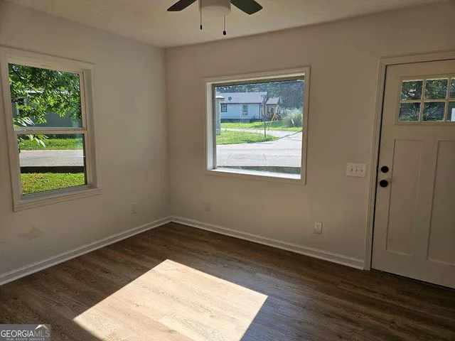 a view of an empty room with wooden floor and a window