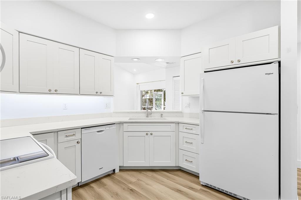 661 Windsor Square, Unit 101 Naples, FL 34104 - Photo 13 of 40 a kitchen with white cabinets and white refrigerator