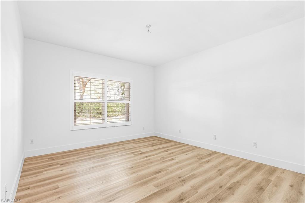 661 Windsor Square, Unit 101 Naples, FL 34104 - Photo 16 of 40 an empty room with wooden floor and windows
