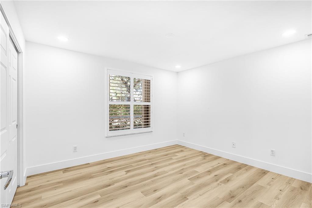 661 Windsor Square, Unit 101 Naples, FL 34104 - Photo 23 of 40 an empty room with wooden floor and windows