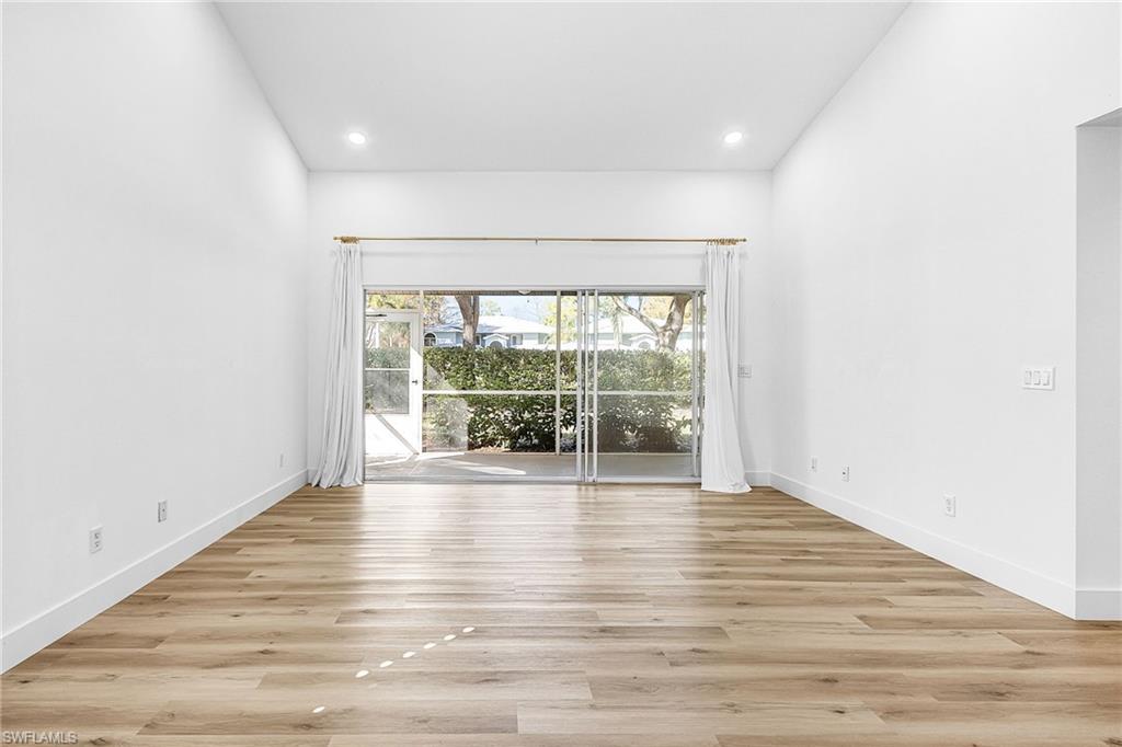 661 Windsor Square, Unit 101 Naples, FL 34104 - Photo 4 of 40 a view of an empty room with wooden floor and a window