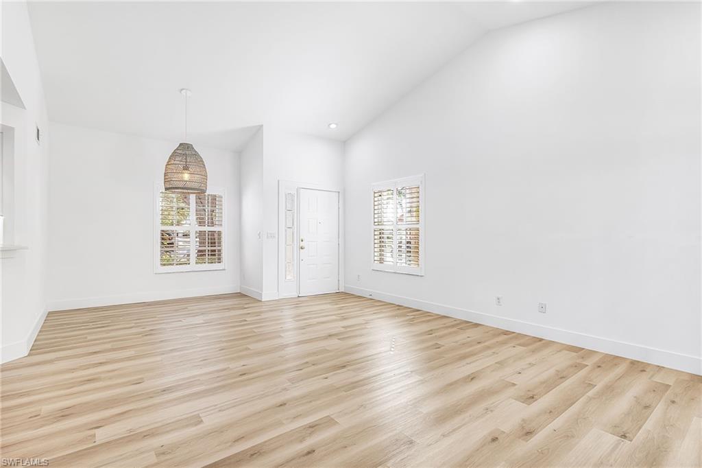 661 Windsor Square, Unit 101 Naples, FL 34104 - Photo 8 of 40 an empty room with wooden floor and windows