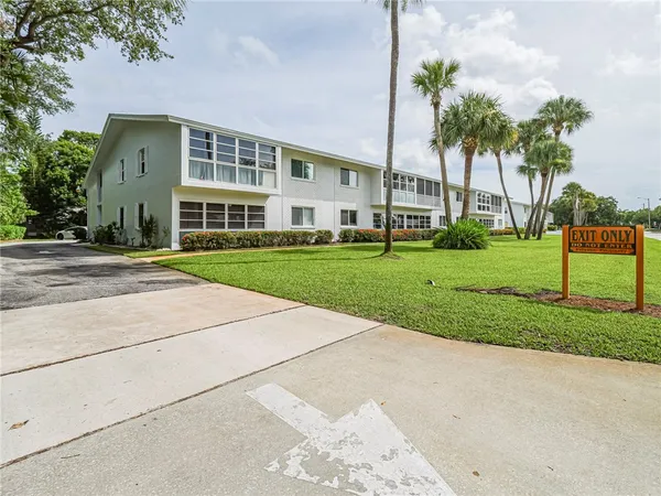 a view of a big building with a big yard and large trees