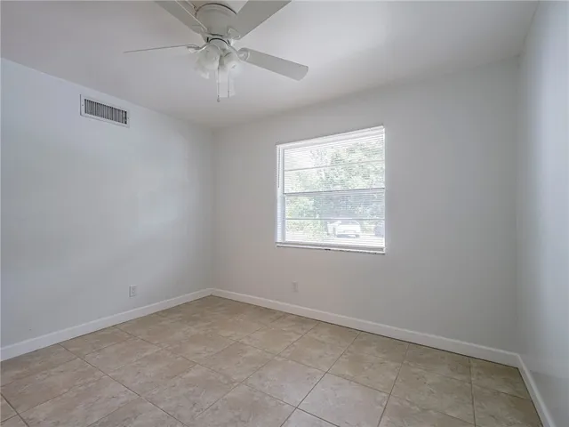 an empty room with a window and a fan
