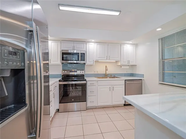 a kitchen with granite countertop a stove sink and refrigerator