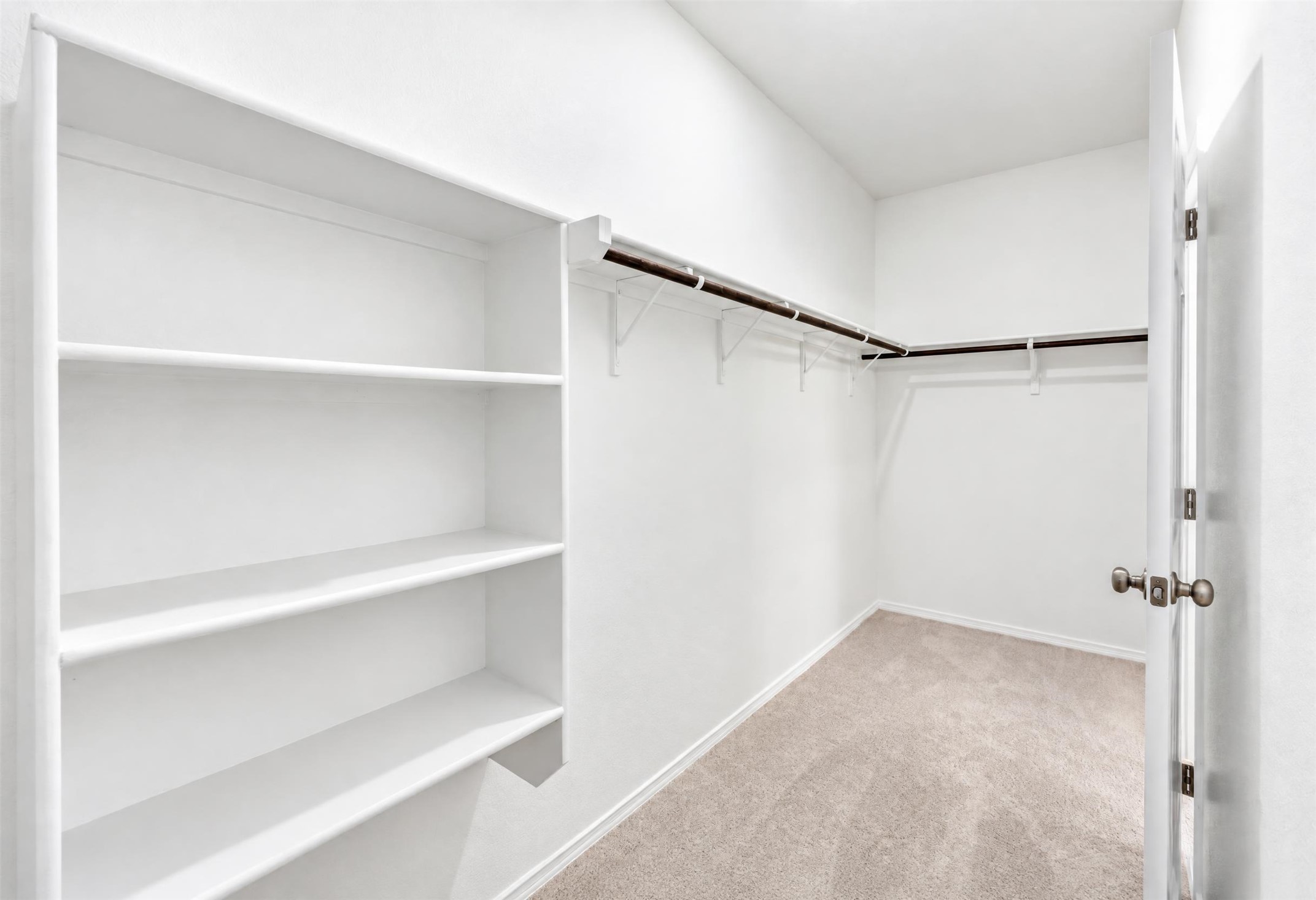 545 Henry Milton Road Georgetown, TX 78626 - Photo 8 of 33 Ample built-in shelving and hanging rods maximize storage in this carpeted walk-in closet.