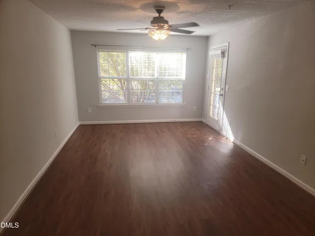 an empty room with wooden floor chandelier fan and windows