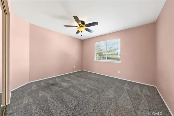 an empty room with a window and a fan