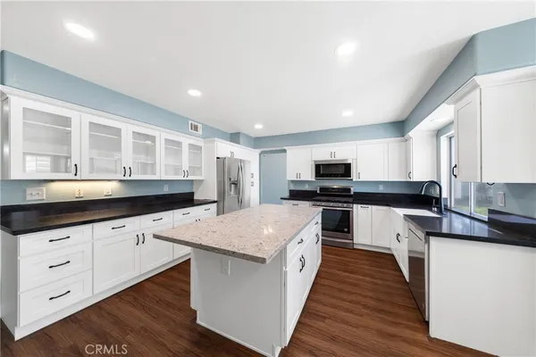 a kitchen with granite countertop a sink and cabinets with wooden floor