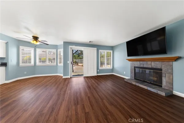 an empty room with windows fireplace and wooden floor