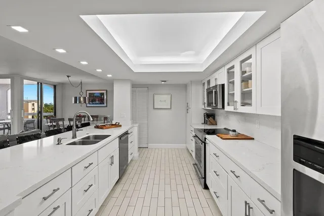 a large white kitchen with stainless steel appliances granite countertop a lot of counter space and wooden floors