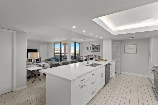 a large white kitchen with a sink and dishwasher a stove with wooden floor