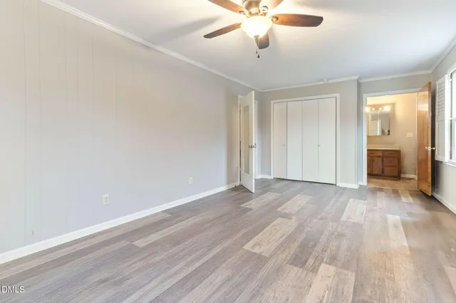 an empty room with wooden floor and ceiling fan