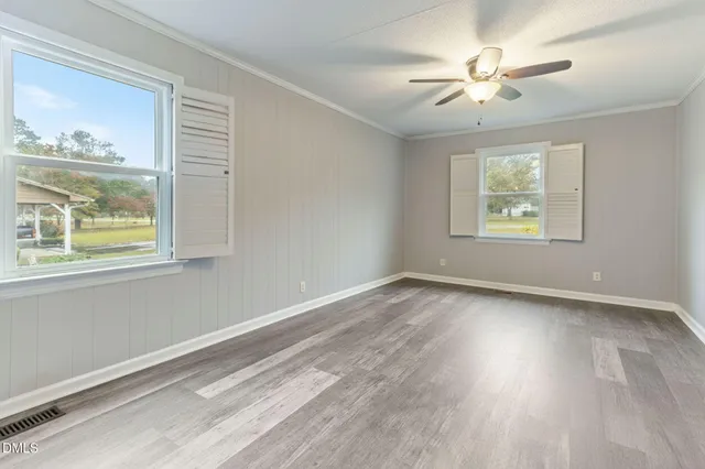 a view of an empty room with a window and wooden floor