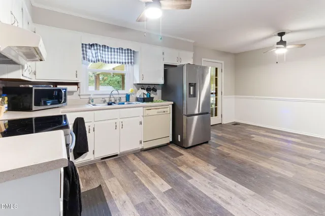 a kitchen with stainless steel appliances a stove a refrigerator cabinets a dining table and chairs