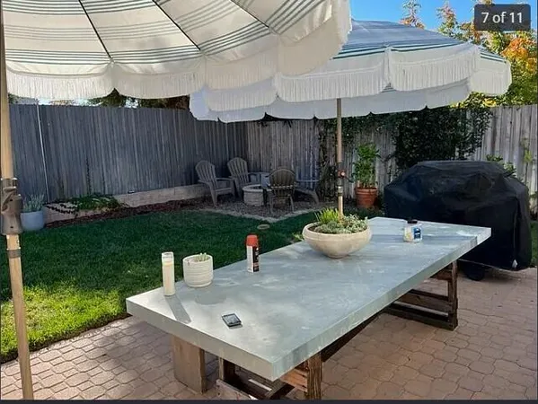a view of a backyard with table and chairs potted plants and wooden fence