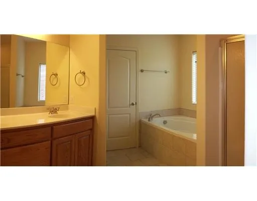 a bathroom with a granite countertop sink a mirror a bathtub and shower