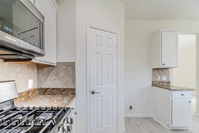 a kitchen with white cabinets and a stove