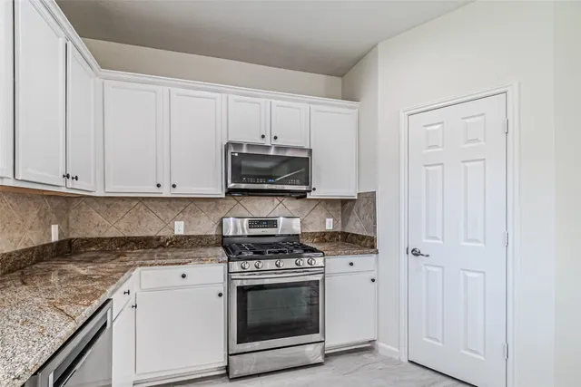 a kitchen with granite countertop white cabinets and stainless steel appliances