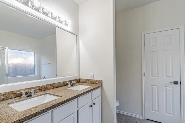 a bathroom with a granite countertop double vanity and a mirror