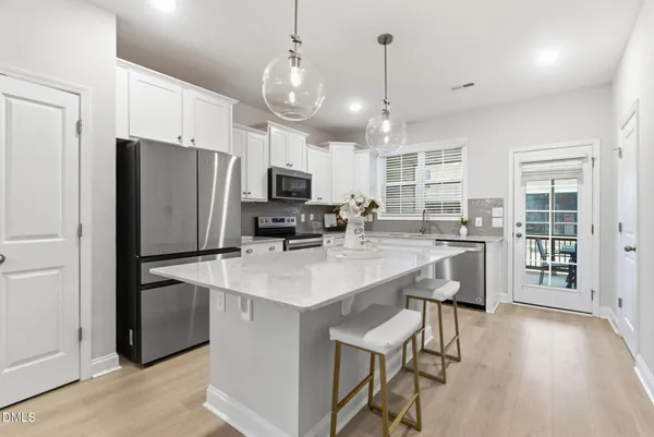 a kitchen with stainless steel appliances a refrigerator a stove a sink a dining table and chairs