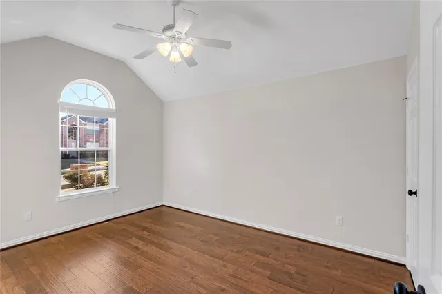 an empty room with wooden floor chandelier fan and windows