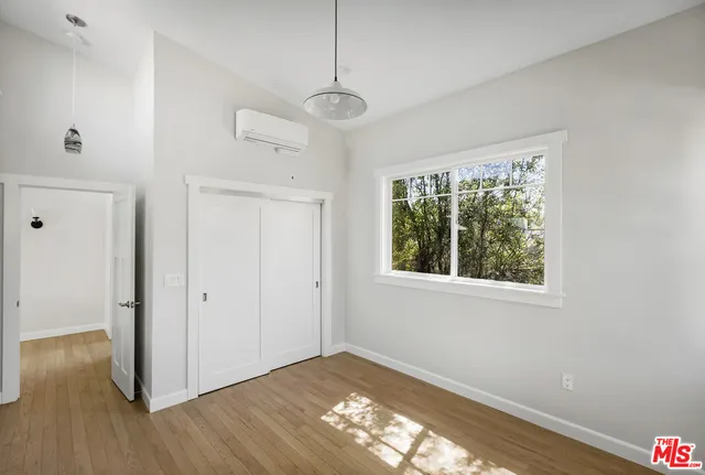 a view of an empty room with wooden floor and a window