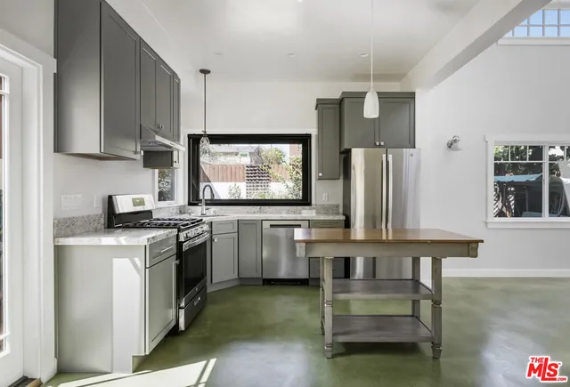 a kitchen with kitchen island a counter top space appliances and a window