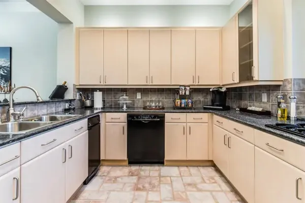 a kitchen with a sink dishwasher a stove and white cabinets