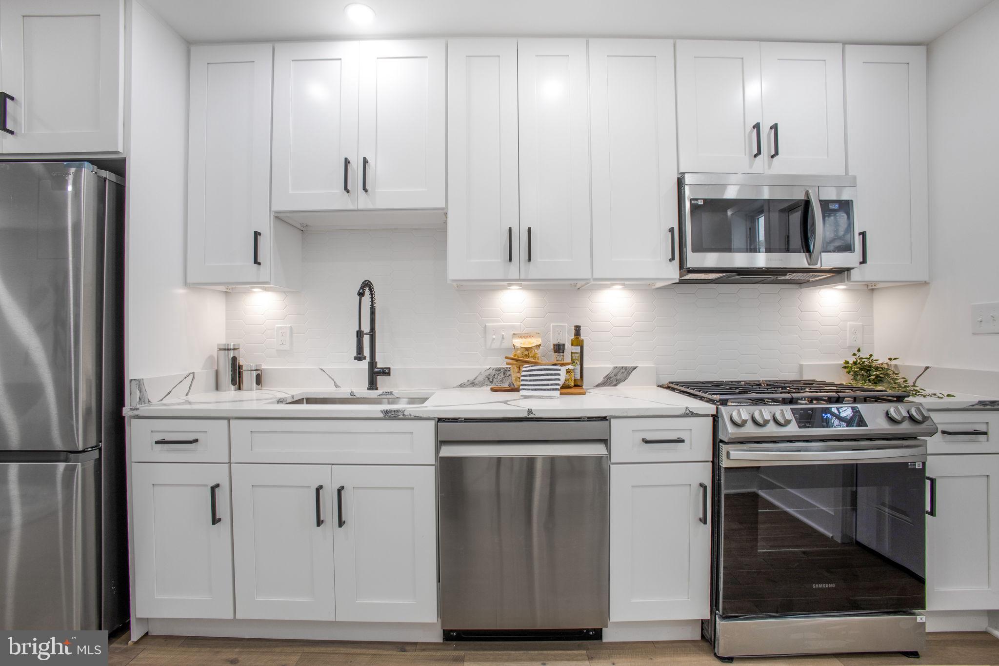 702 19th Street Northeast Washington, DC 20002 - Photo 9 of 38 a kitchen with stainless steel appliances granite countertop a stove a sink and a refrigerator with white cabinets