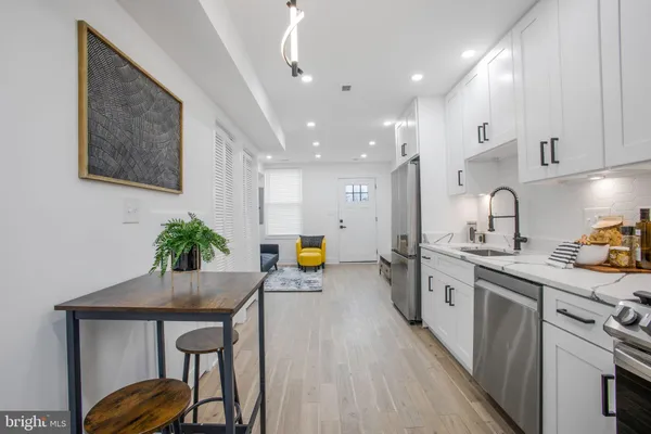 a kitchen with stainless steel appliances a sink a stove a refrigerator cabinets and living room