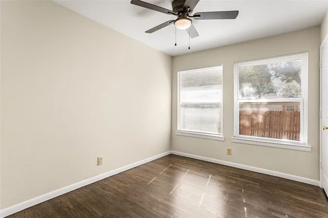an empty room with wooden floor fan and windows