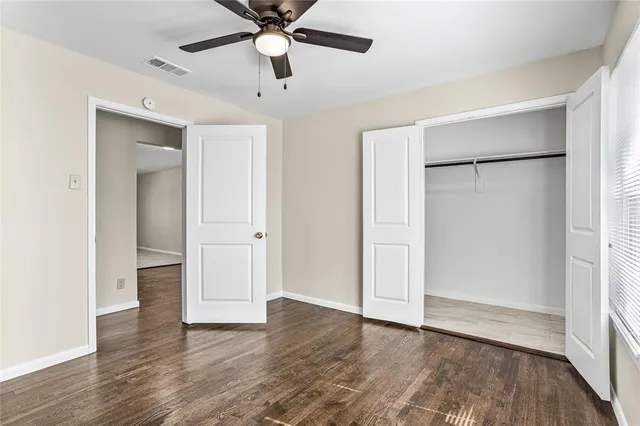 an empty room with wooden floor and a ceiling fan