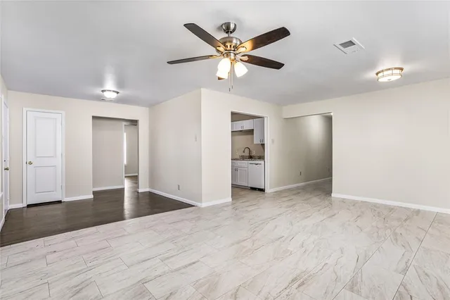 a view of an empty room with wooden floor and a ceiling fan