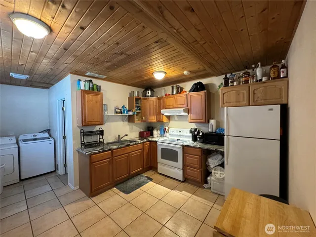 a kitchen with stainless steel appliances granite countertop a sink a stove a refrigerator cabinets and chairs