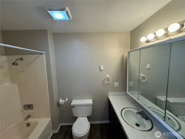 a bathroom with a granite countertop toilet sink shower and mirror