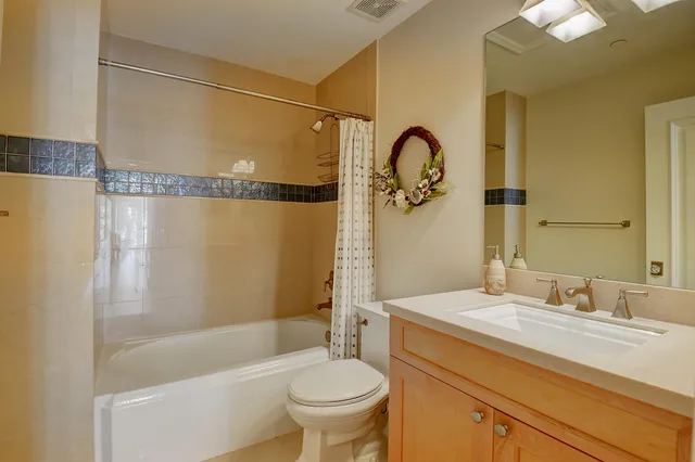 a bathroom with a granite countertop bathtub sink vanity mirror and toilet