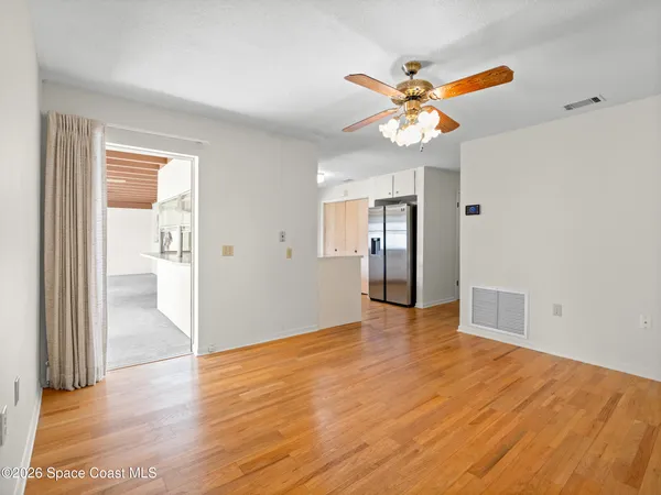 a view of an empty room with window and a ceiling fan