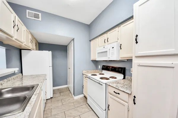 a kitchen with granite countertop a sink stove and cabinets