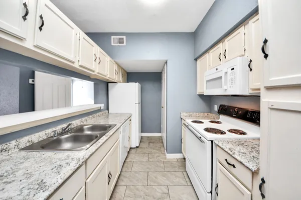 a kitchen with granite countertop a sink stove and cabinets