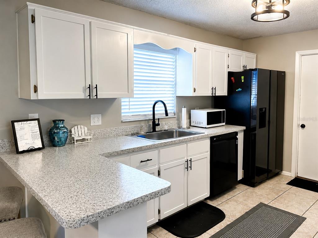 11177 Elgin Boulevard Spring Hill, FL 34608 - Photo 4 of 10 a kitchen with stainless steel appliances granite countertop a sink refrigerator and cabinets
