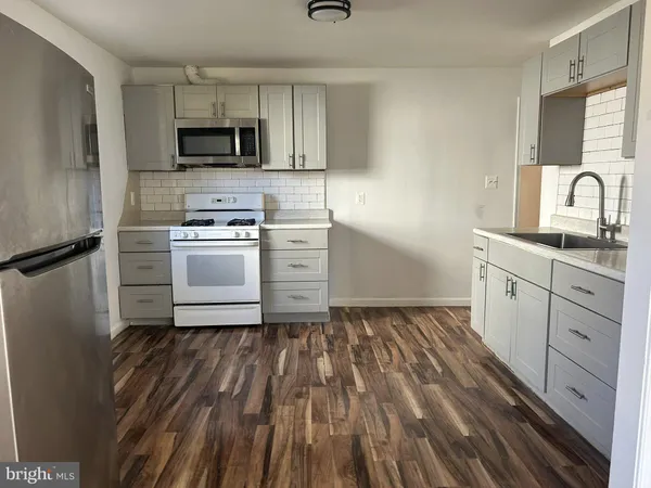 a kitchen with a sink wooden floor and stainless steel appliances