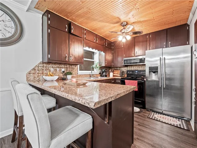 a kitchen with stainless steel appliances granite countertop a table chairs and a refrigerator
